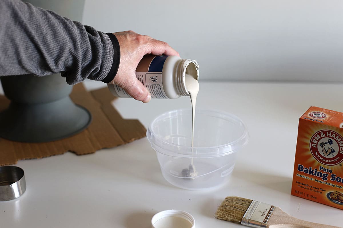 Pouring chalk paint into a container to mix with baking soda.