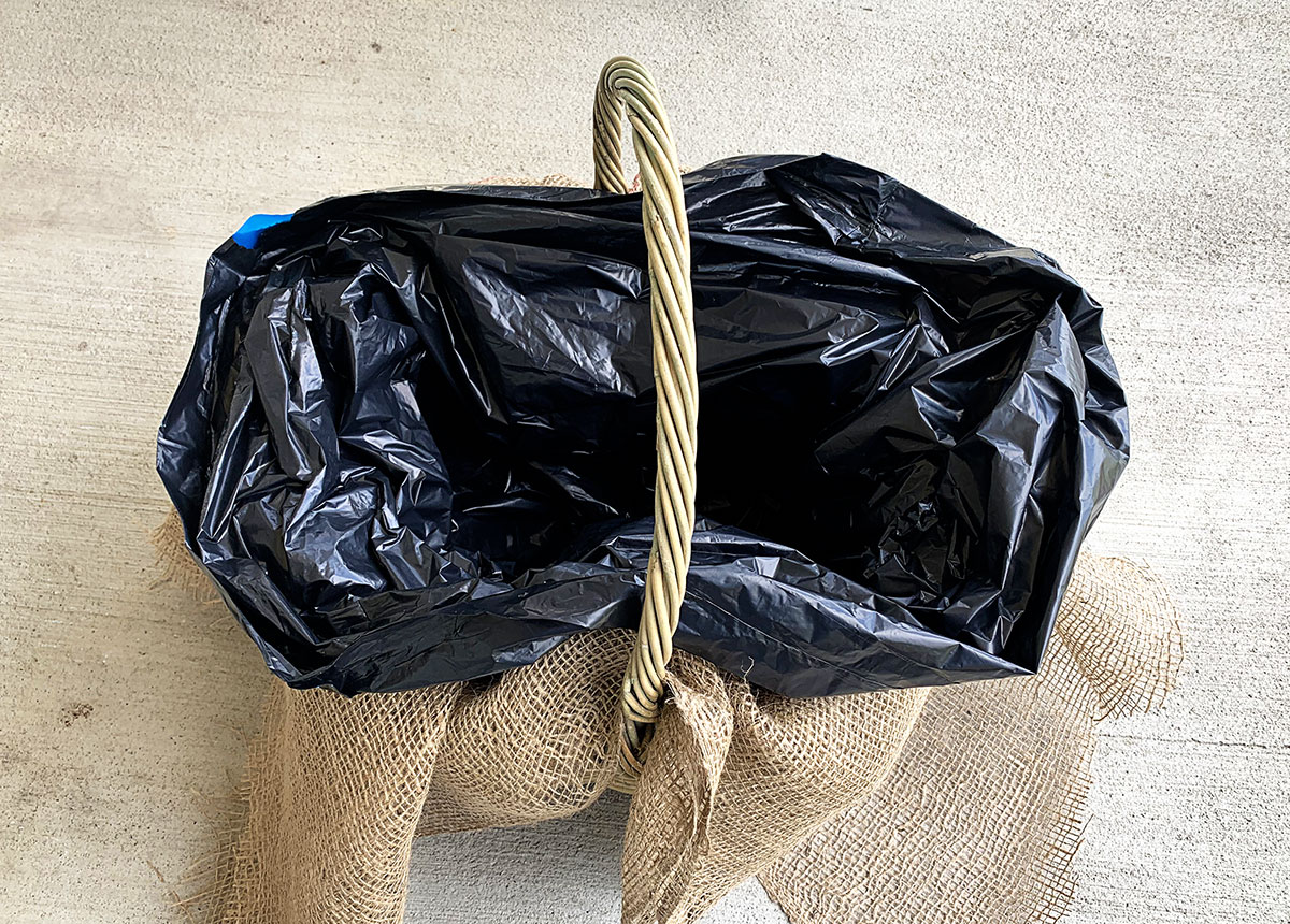 Lining a wicker basket with a garbage bag to contain drainage.