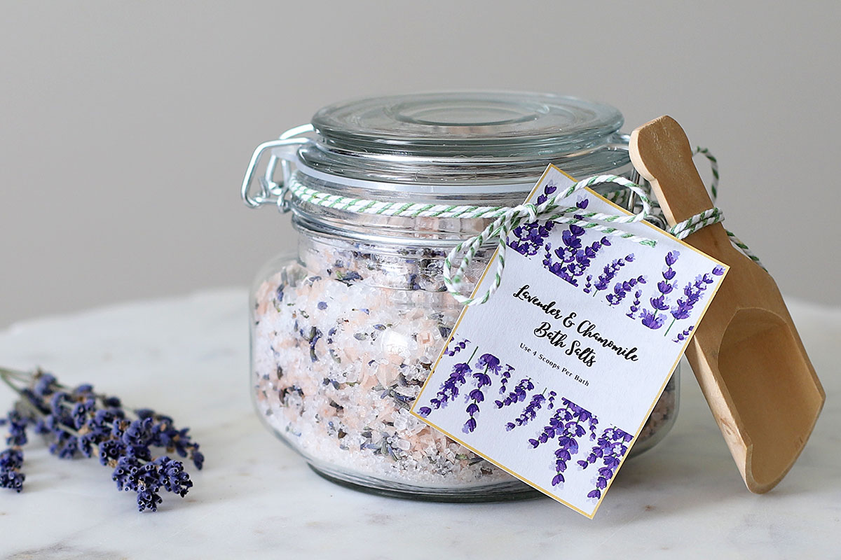 DIY lavender and chamomile bath salts in a glass jar with a wooden scoop.