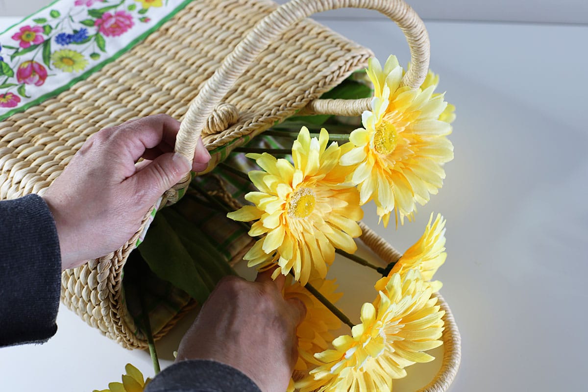 Yellow daisies being stuffed into the purse to be used as a wreath.