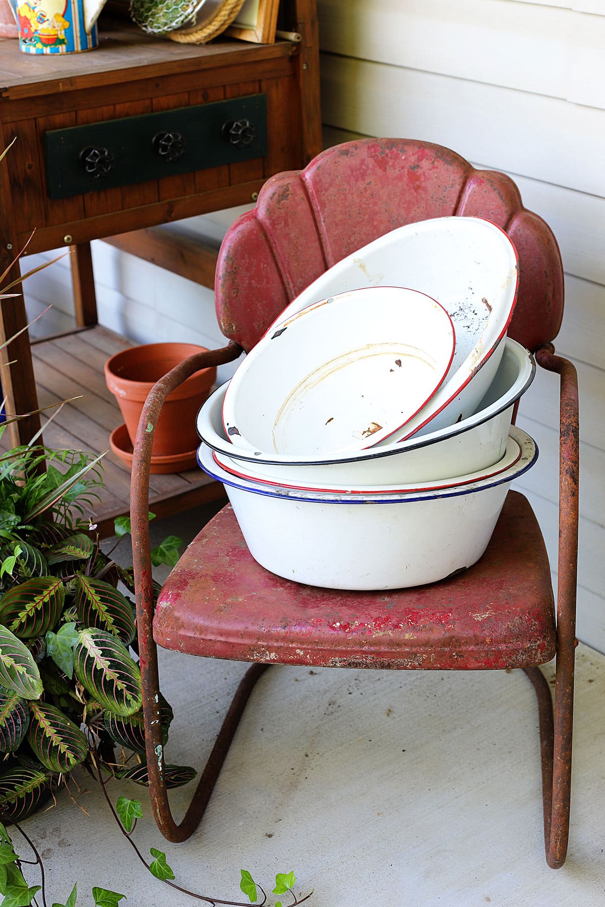 Vintage enamelware wash basins sitting on a red metal motel chair. 