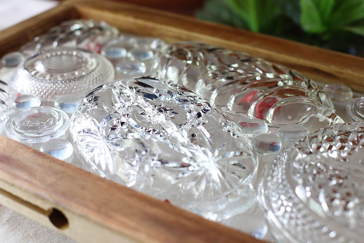 Pieces of thrift store glassware setting on a window pane.