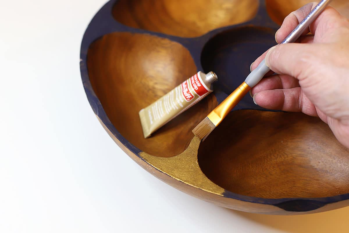 Applying faux gold leaf to a mid century modern wooden bowl.