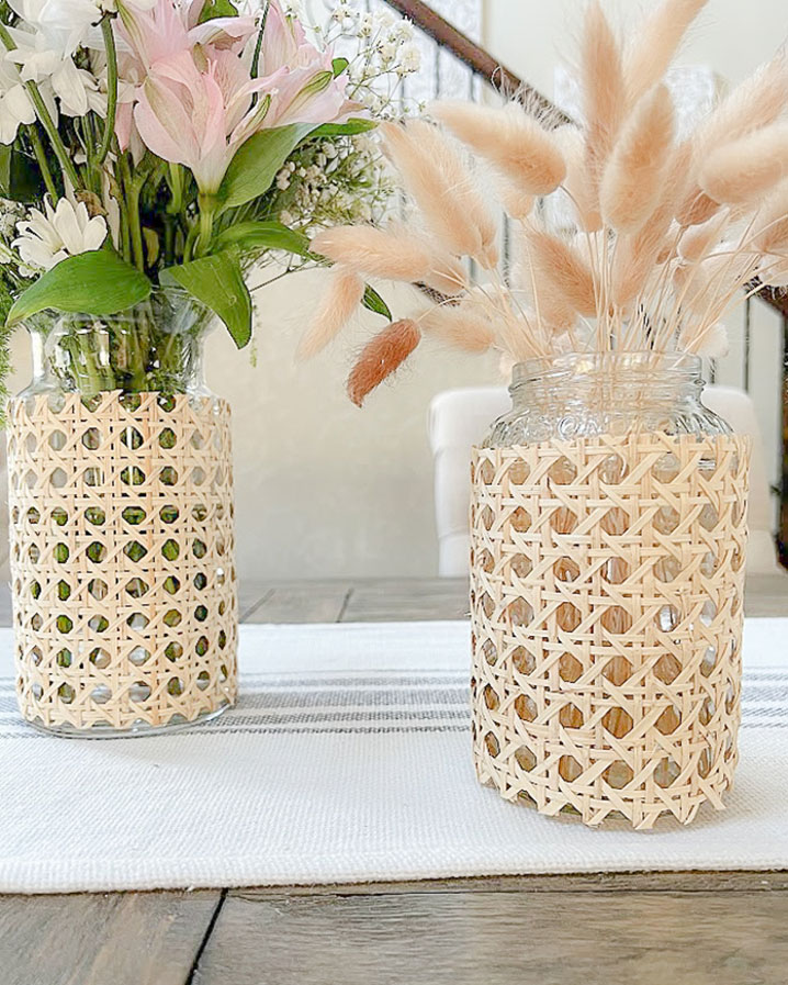 Two cane covered vases sitting on a table.