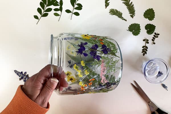 Adding even more flowers to the glass jar.
