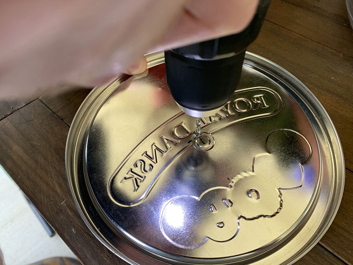 Making a pilot hole in the middle of the tin lid.