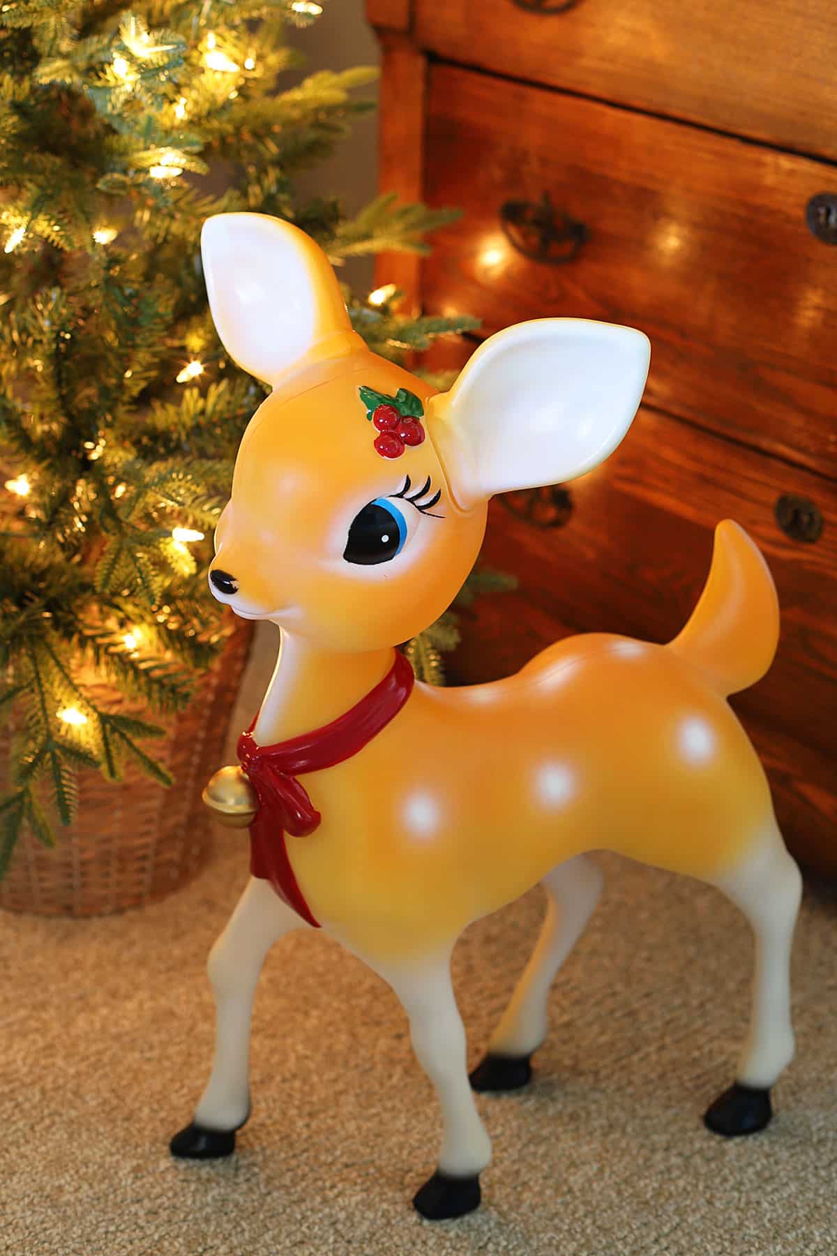Retro reindeer blow mold for Christmas decor. The reindeer has a red bow on its neck and large eyelashes similar to Clarice from the Rudolph The Red Nosed Reindeer movie.