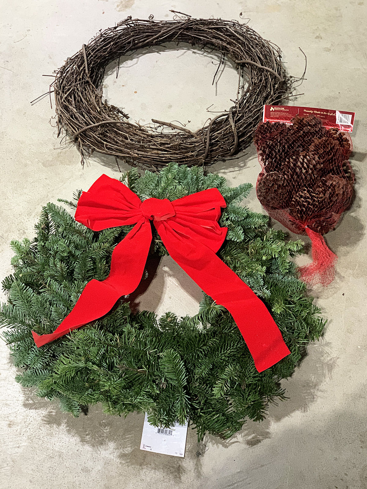Supplies needed for a quick and easy porch urn for your holiday porch - grapevine wreath, fresh greens wreath and a bag of pine cones. All can be found at local hardware or grocery stores. 