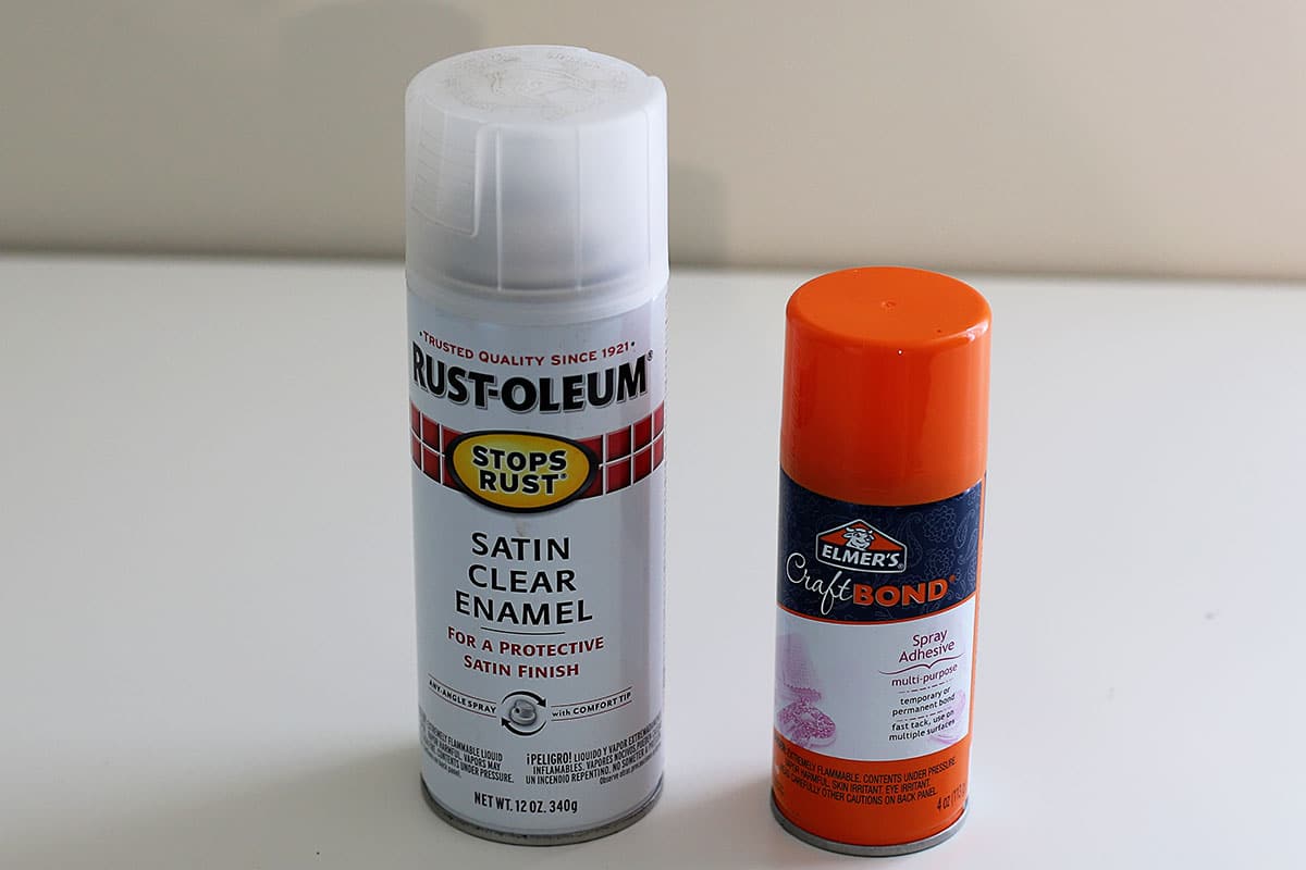 Spray cans of Rust-oleum Satin Clear Enamel protective finish and Elmer's Craft Bond repositionable adhesive.