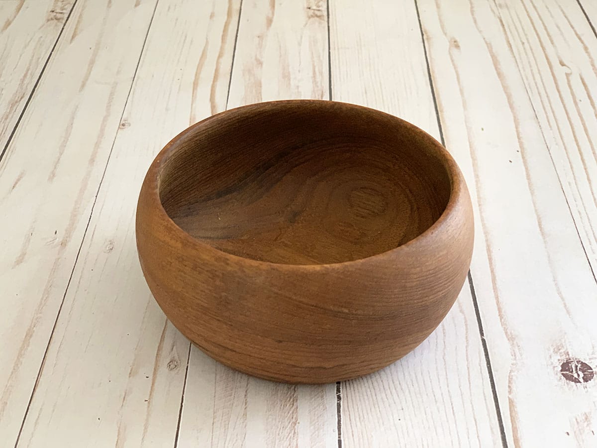 Vintage wooden salad bowl from the thrift store setting on a white barnwood floor.