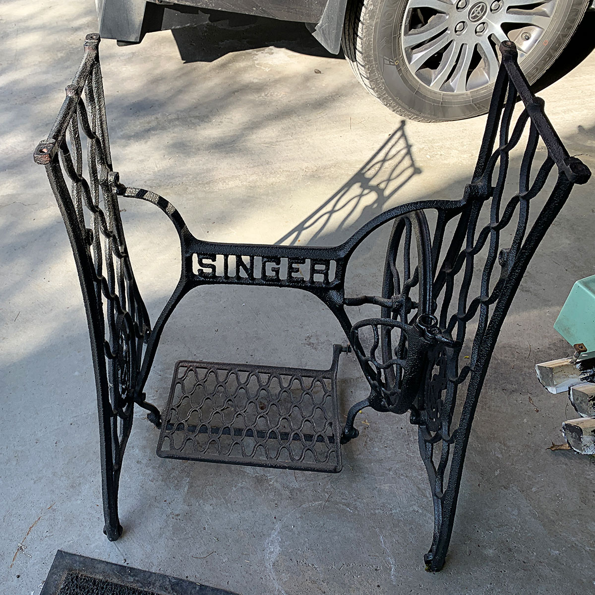 Vintage black cast iron Singer sewing machine base with no top or sewing machine attached.