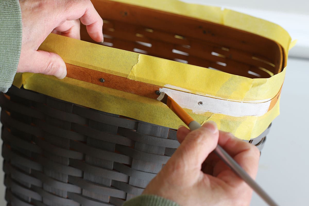 Painting the top rim of the basket with white paint.