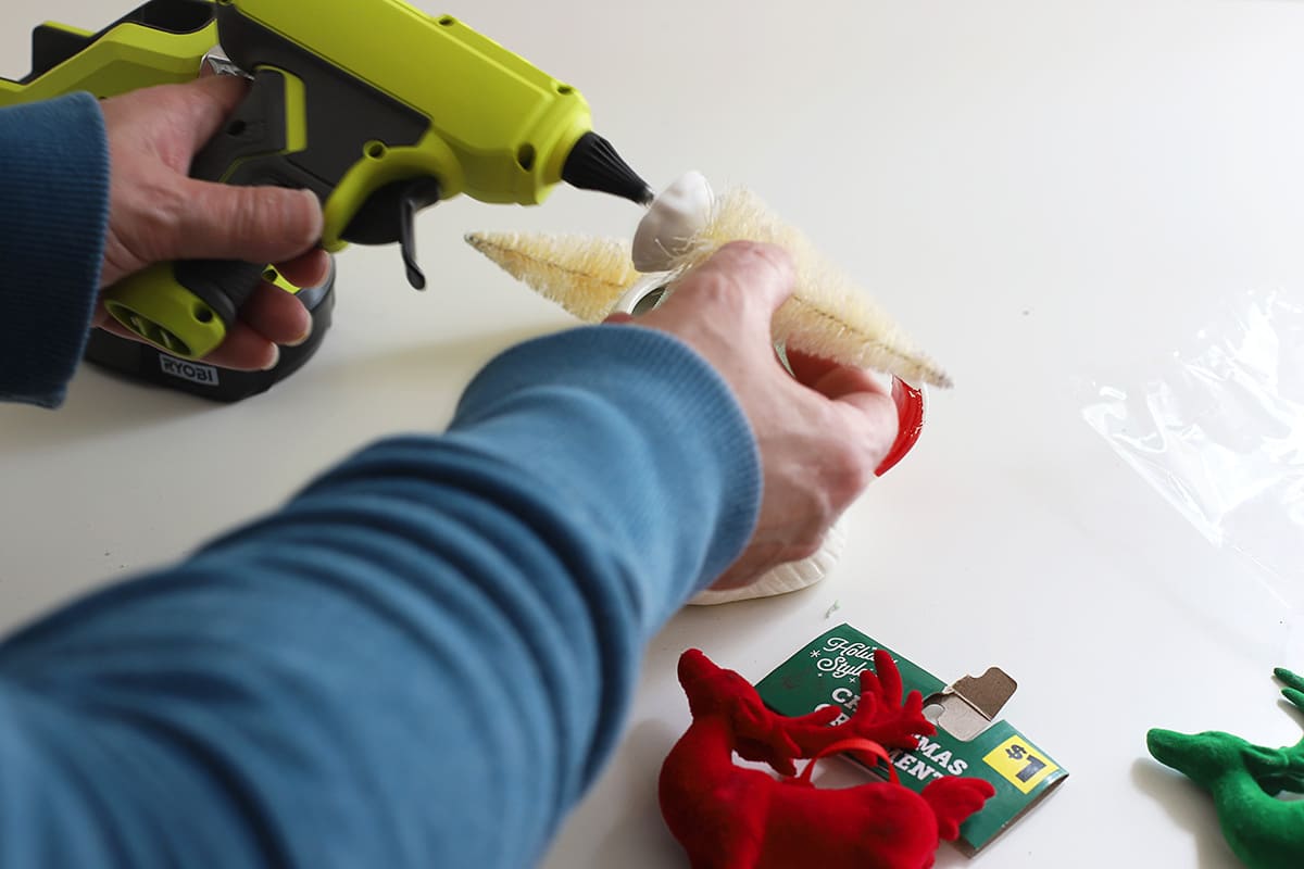 Gluing a bottle brush tree to a holiday arrangement.