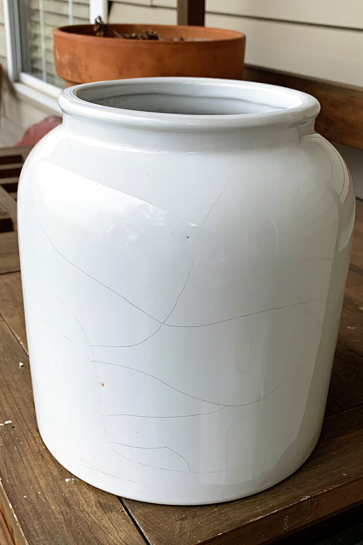 Stoneware crock beverage dispenser with cracks running down the backside.